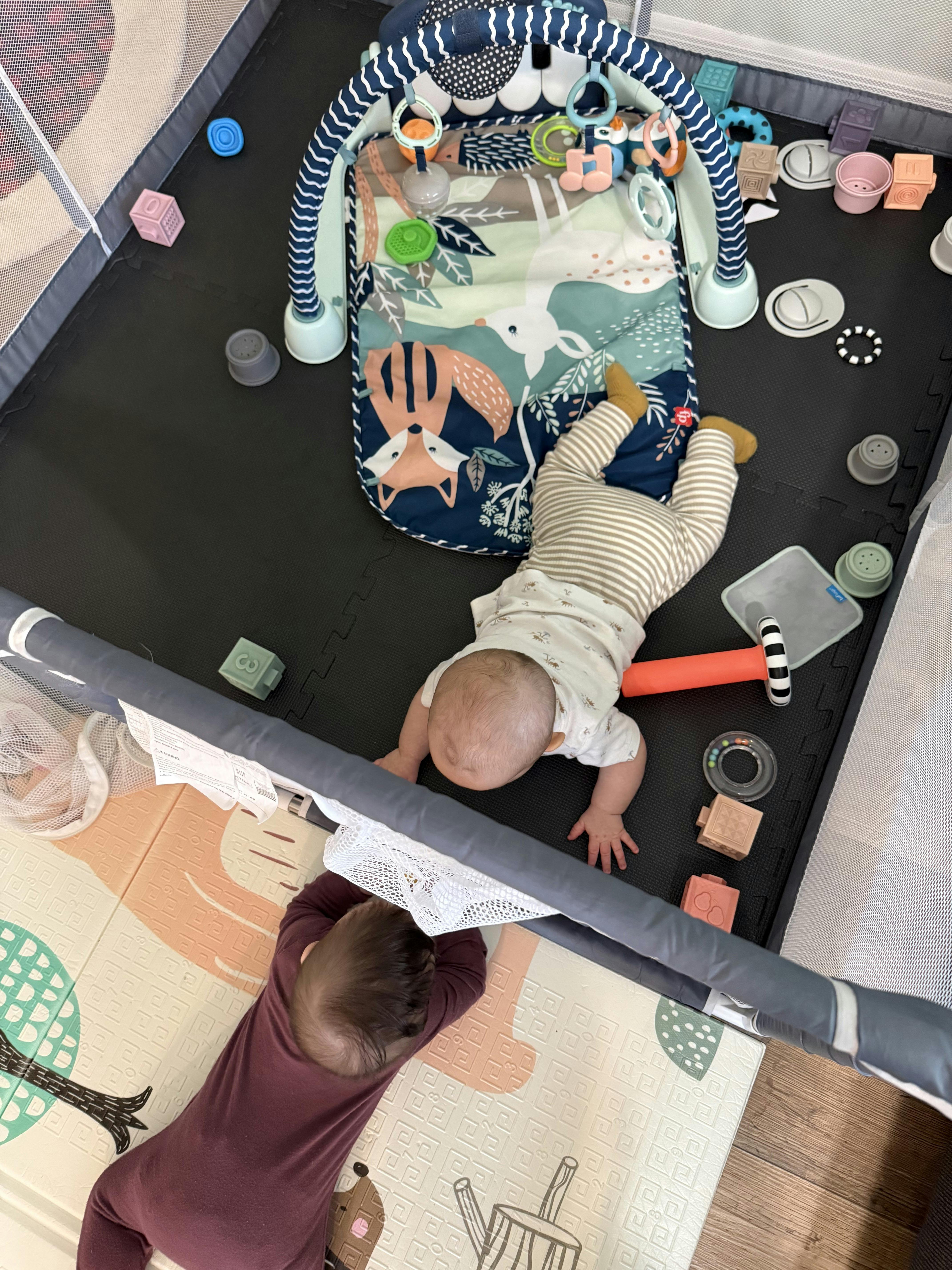 Two children playing on soft mats with toys