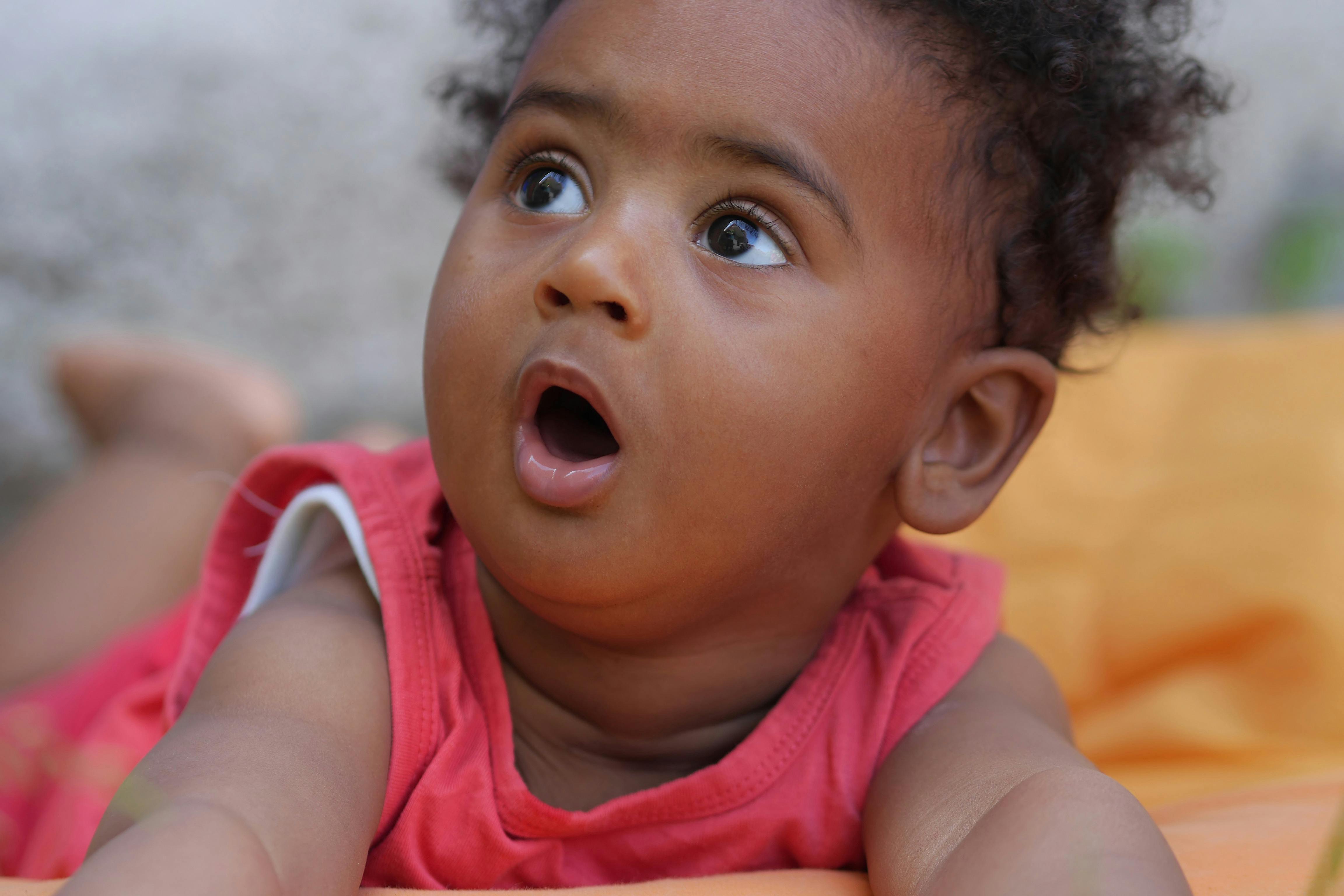 Child lying on stomach with mouth open looking up