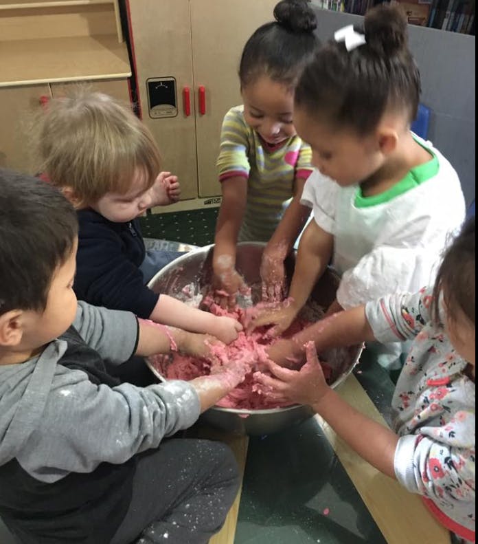 Children playing with pink dough in a large bowl