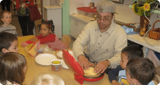 Person making food with children watching in a classroom