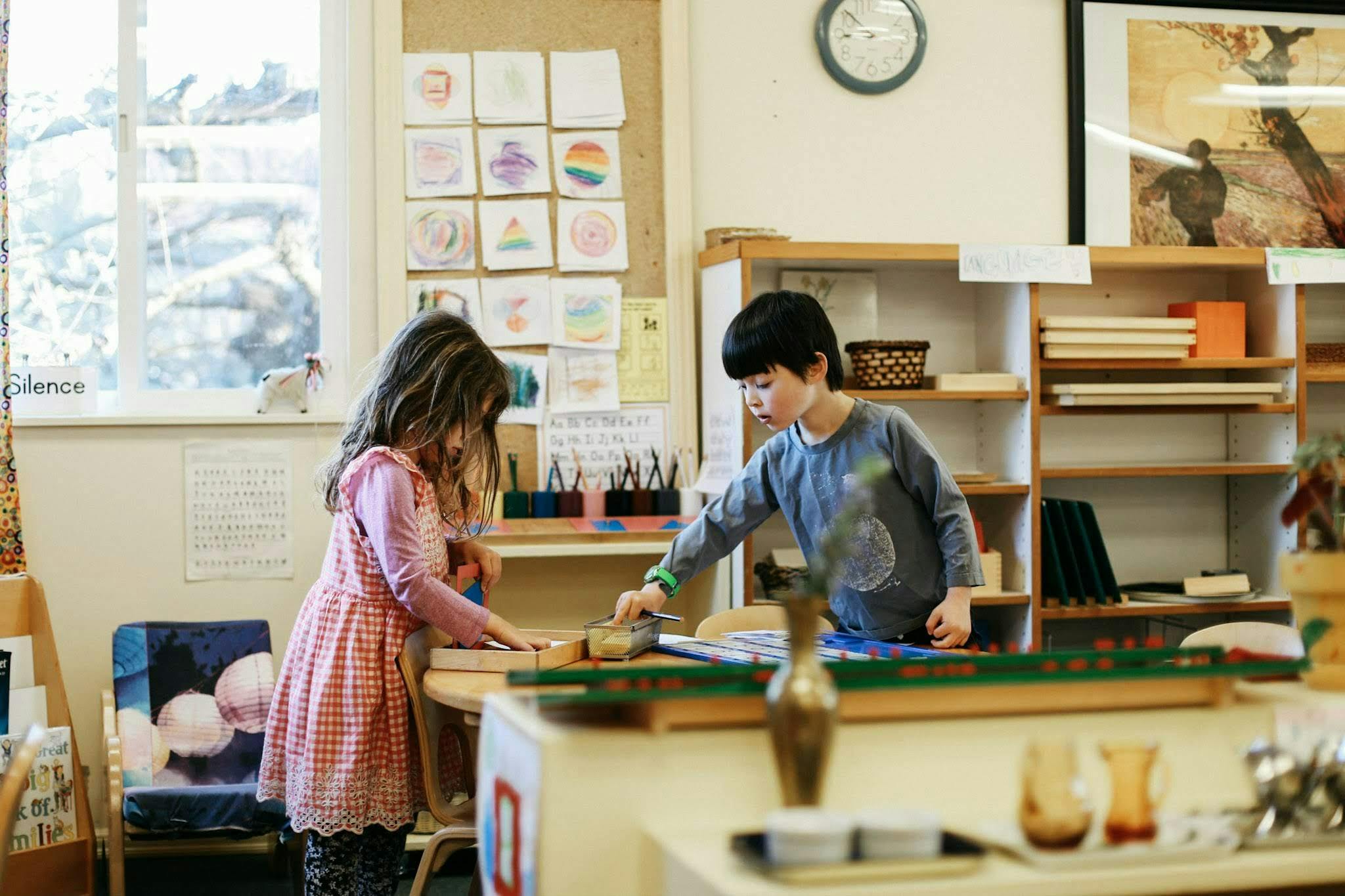Two children working at a table in a classroom
