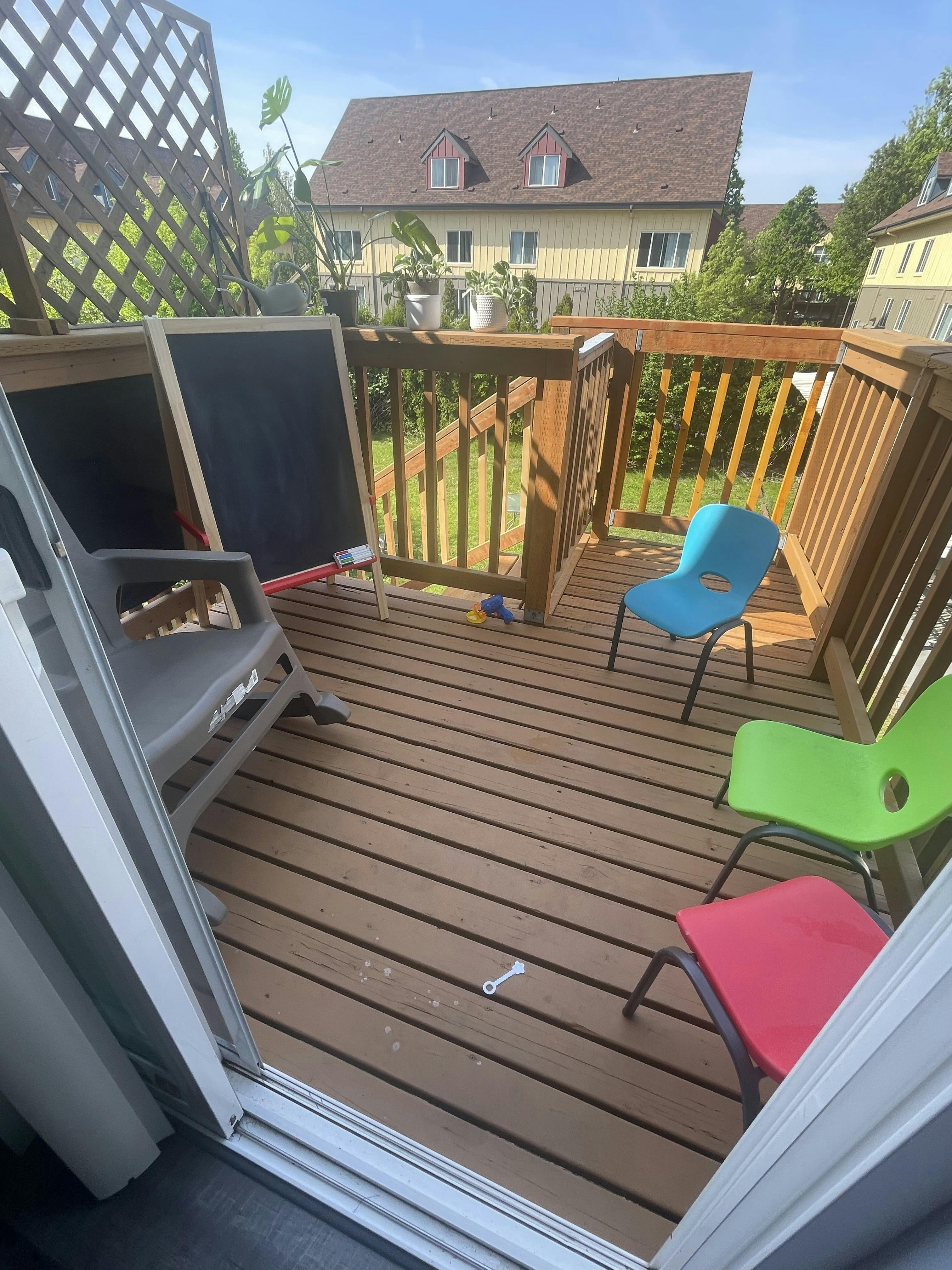 Outdoor deck with a chalkboard, lounge chair, and colorful small chairs