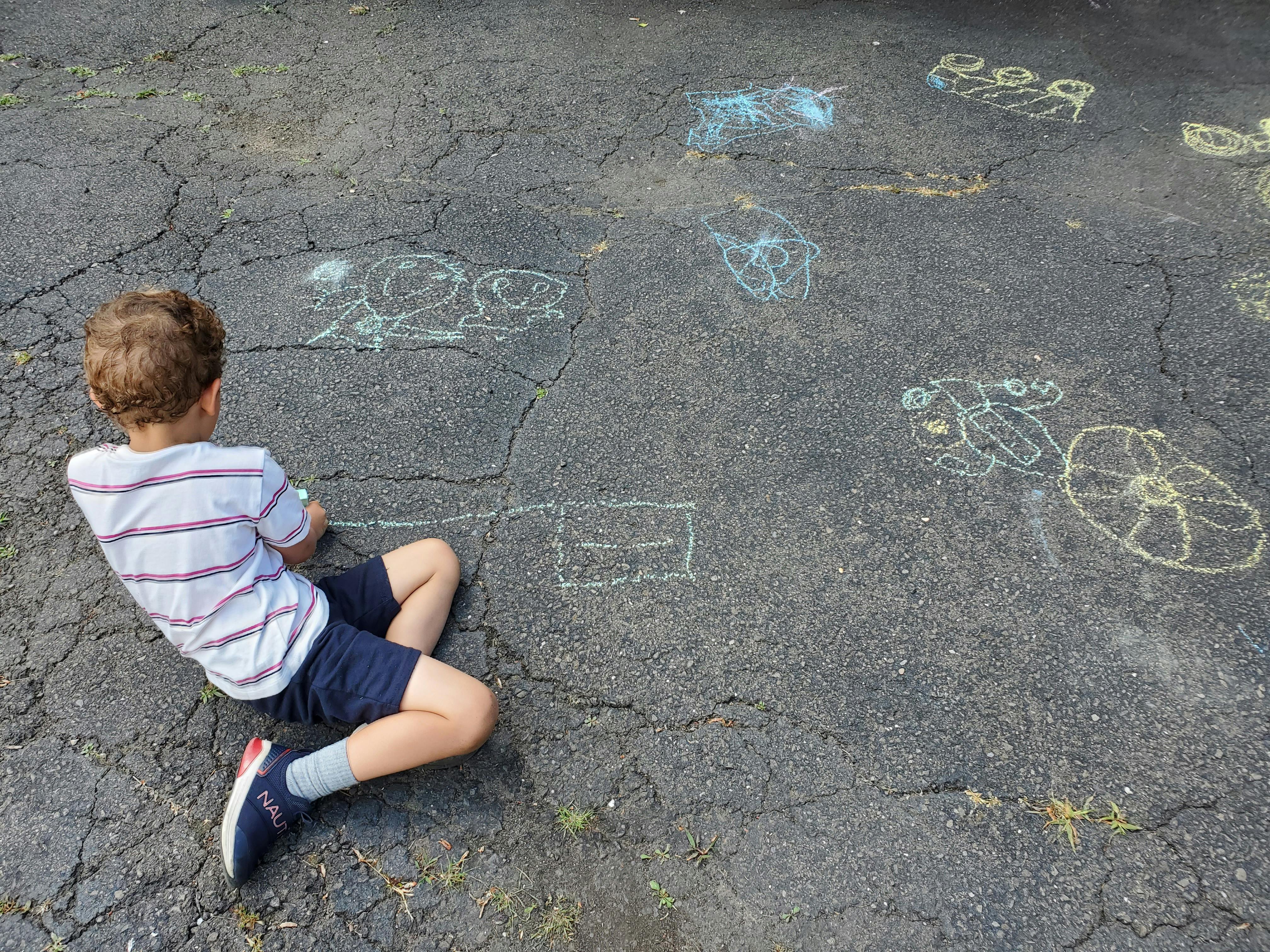 Child drawing with chalk on asphalt