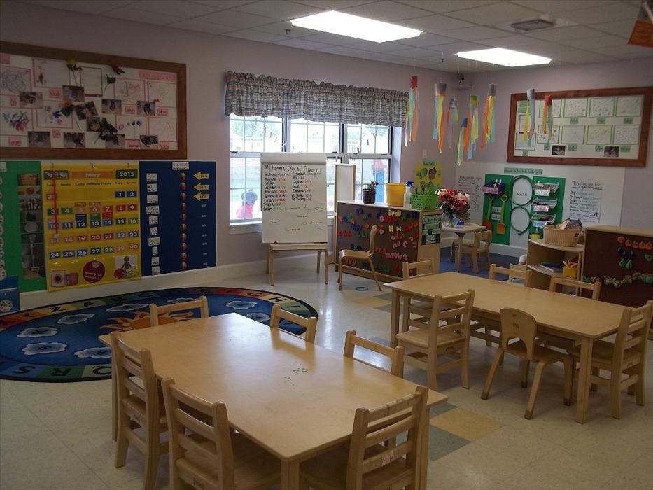 Classroom with small tables and chairs, calendar display, and window