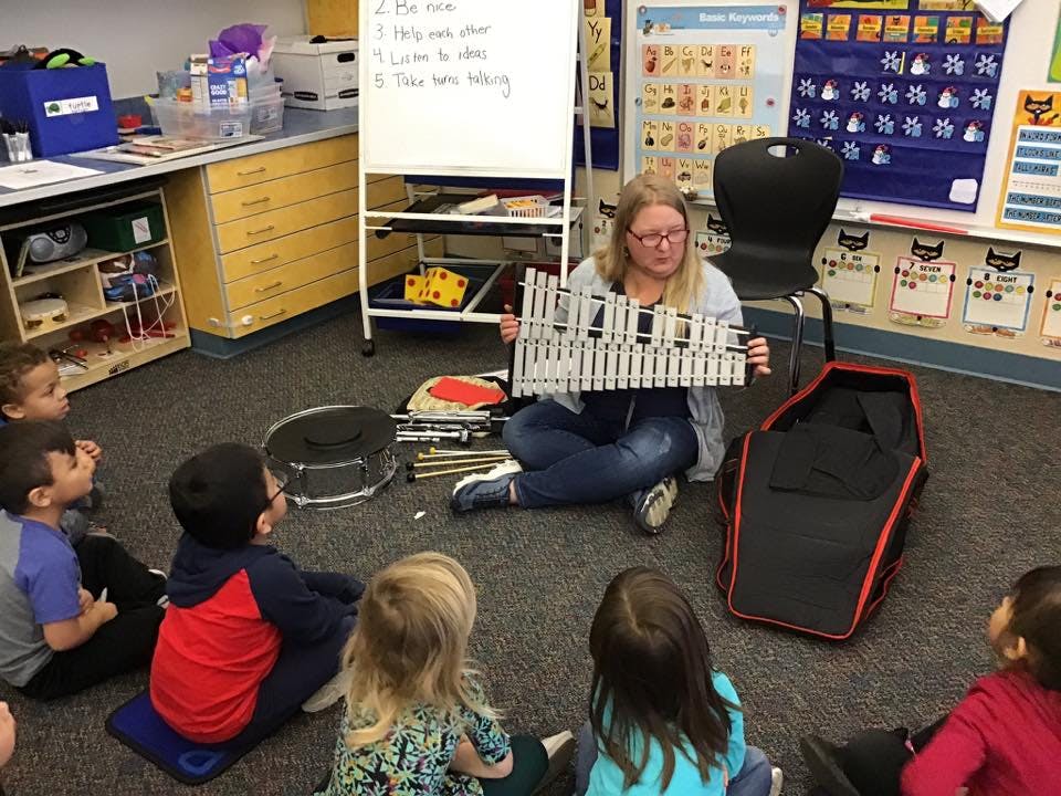 Person sitting on floor holding a glockenspiel for children