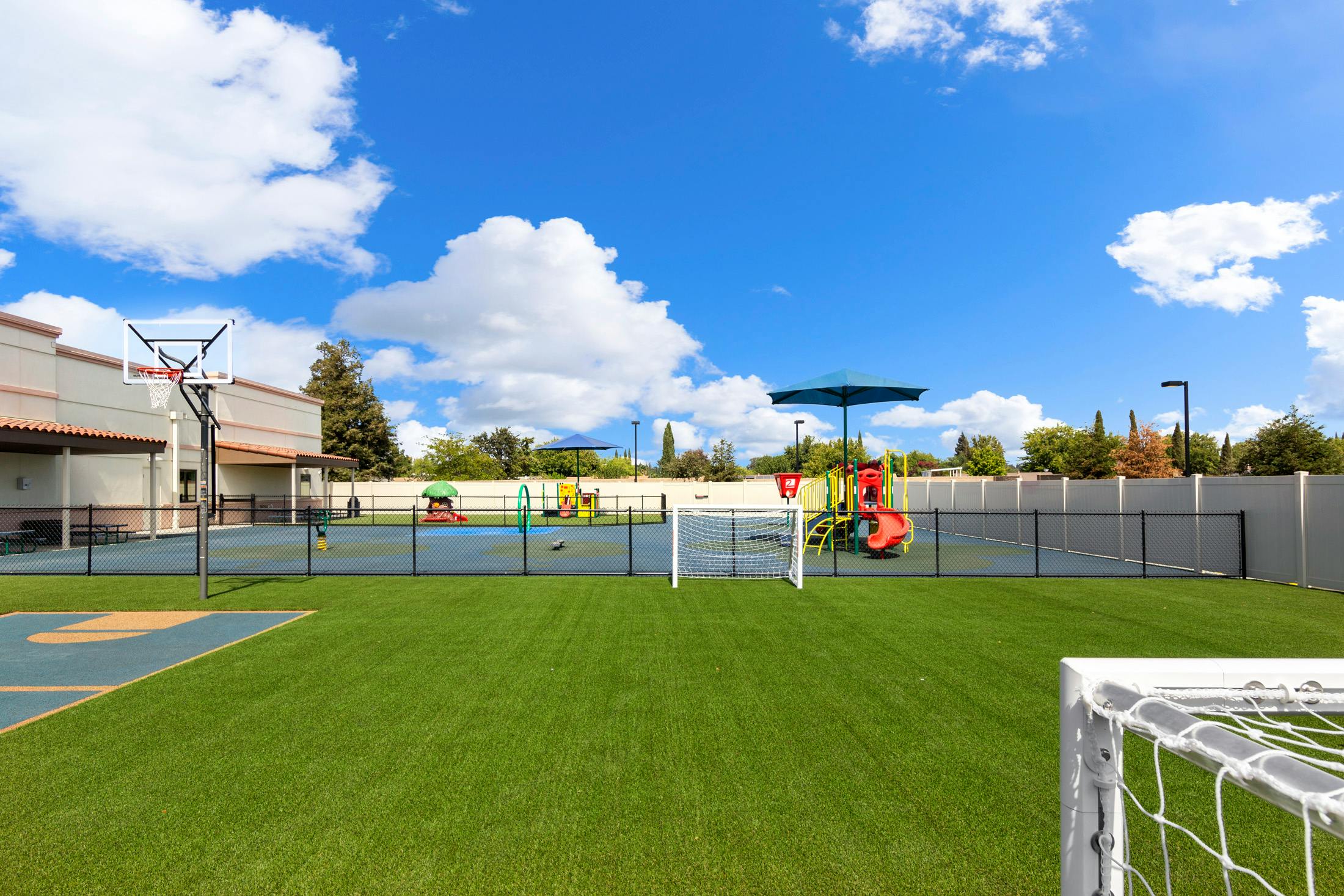 Outdoor playground with artificial turf, basketball court, and soccer goal