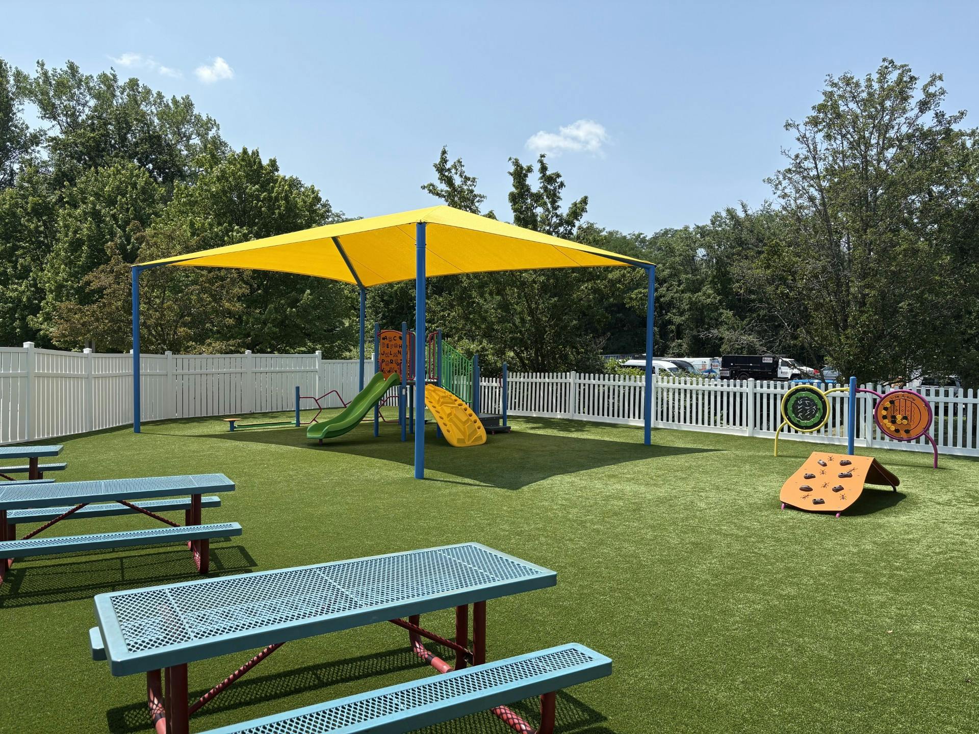 Playground with a yellow shade structure, slides, and picnic tables