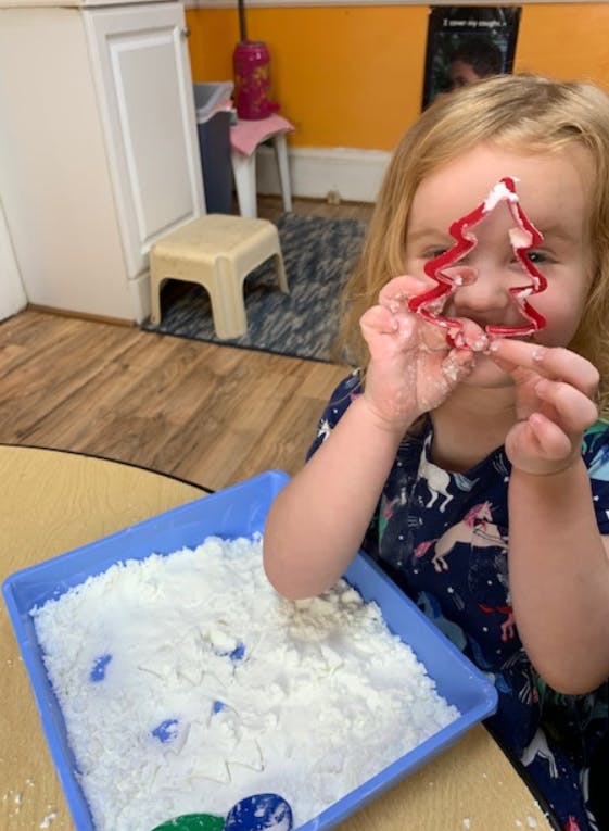 Child holding a Christmas tree cookie cutter over their face