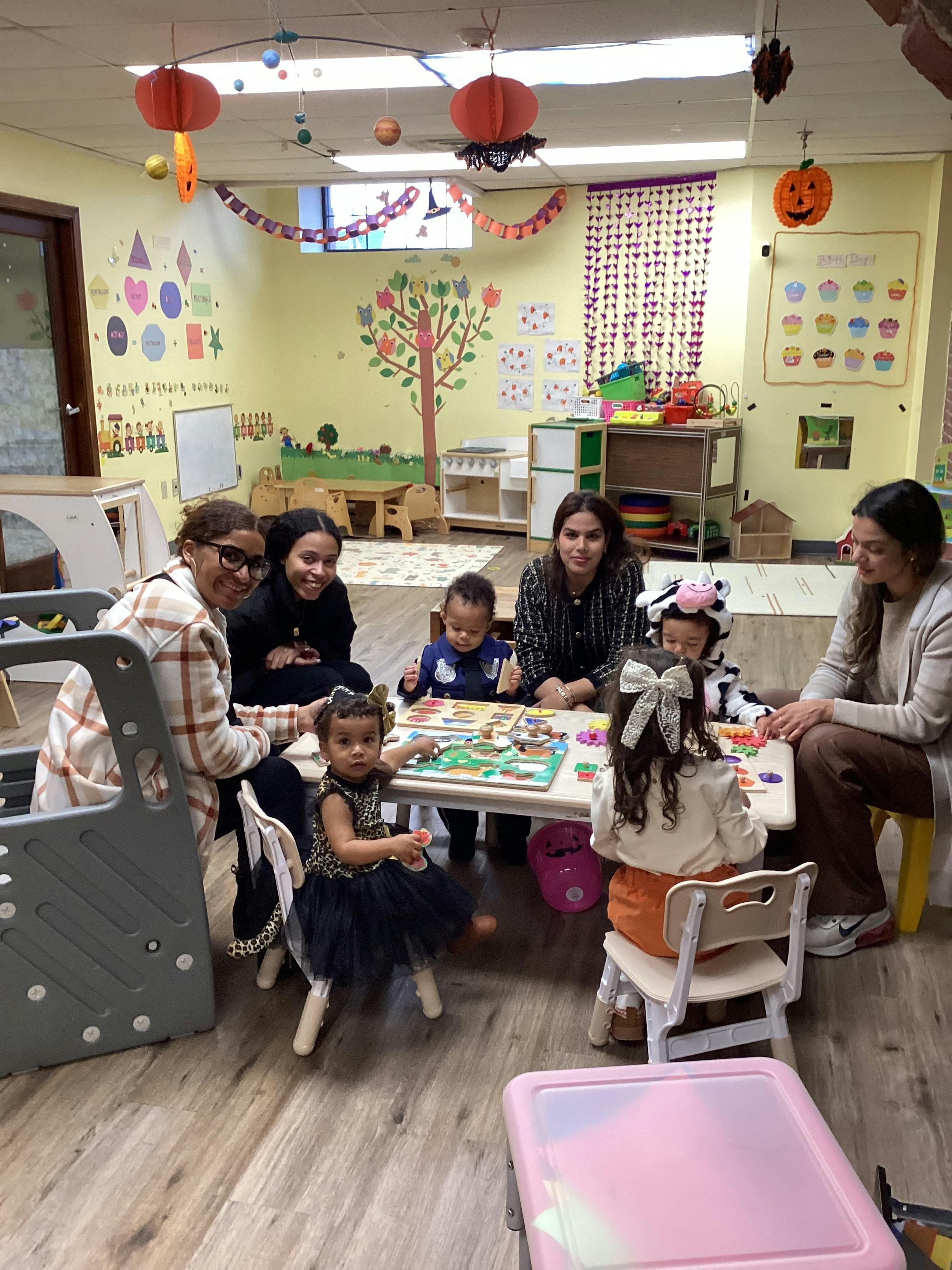 Adults and children sitting around a table in a classroom