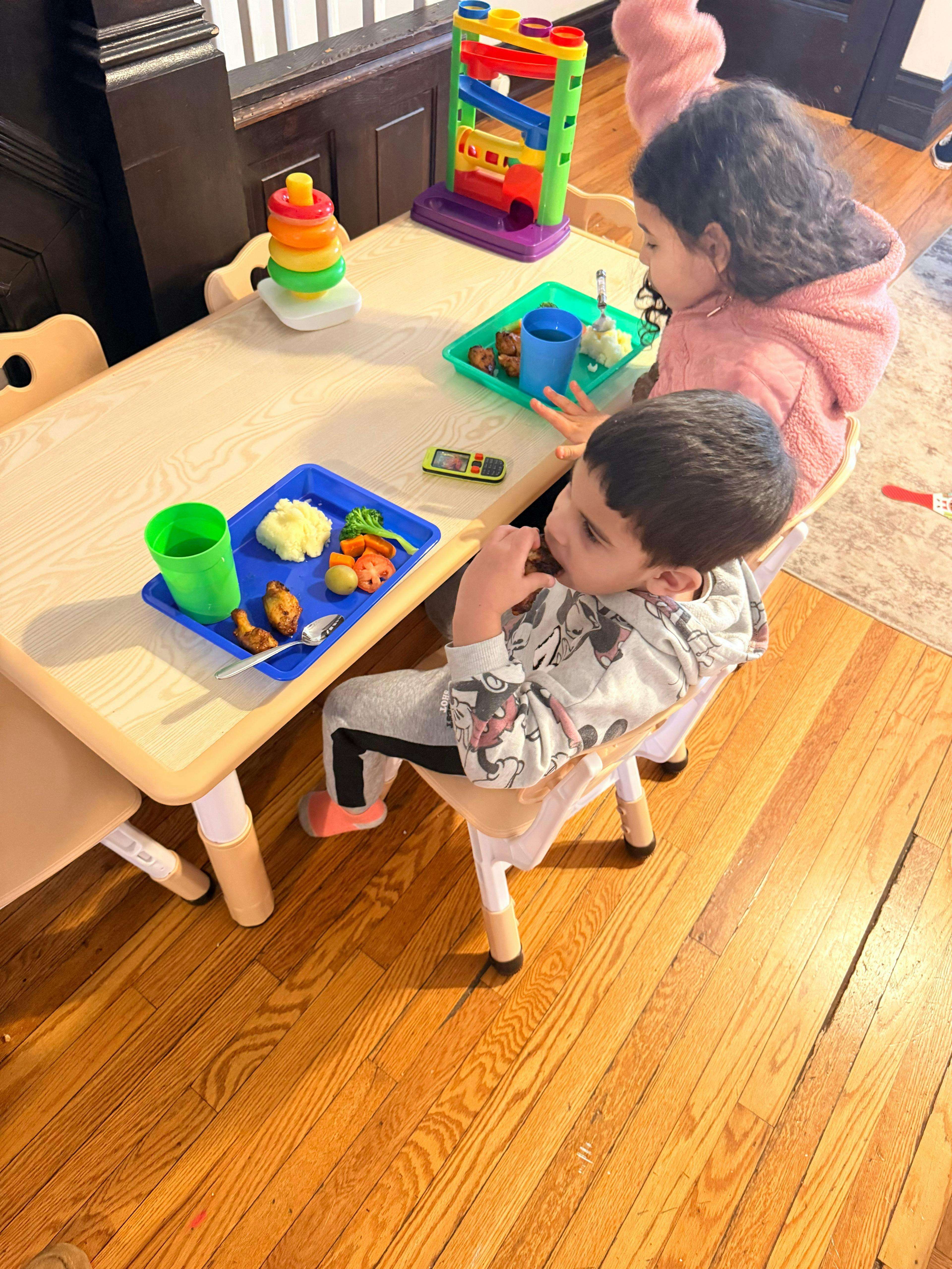 Child in a grey Mickey Mouse sweatshirt eating dinner at a table