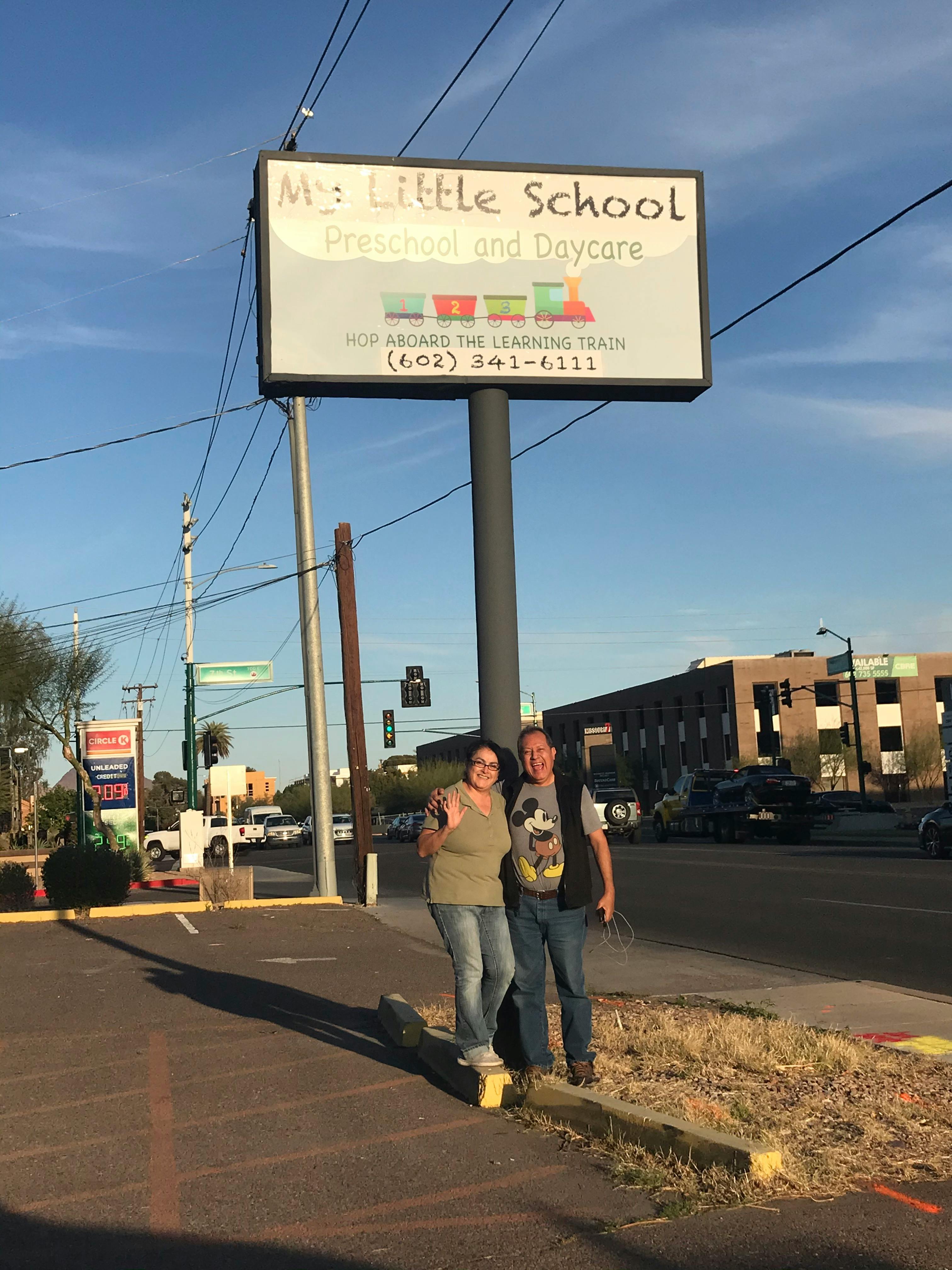 Two people standing under a sign for "My Little School Preschool and Daycare"