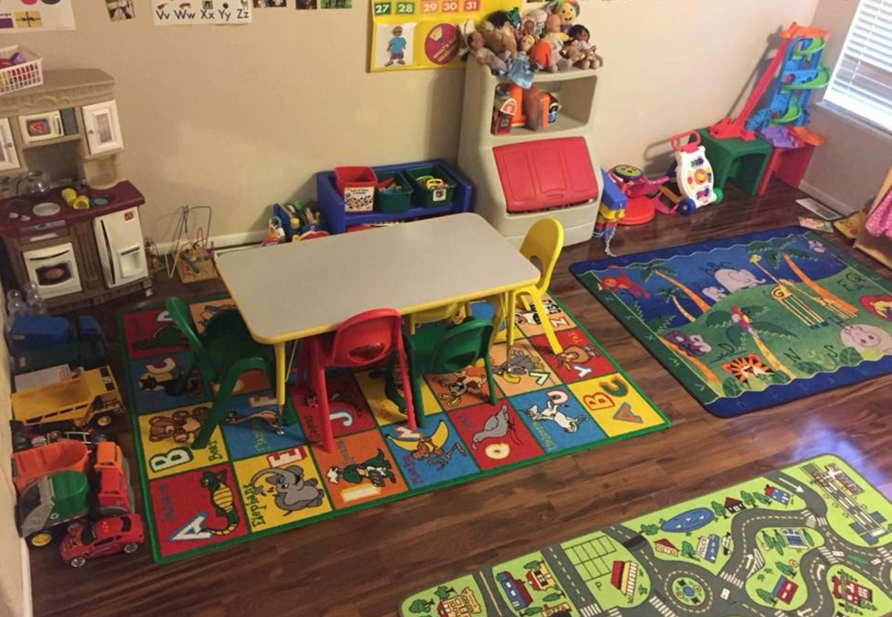 Playroom with small table and chairs, toy kitchen, and colorful rugs