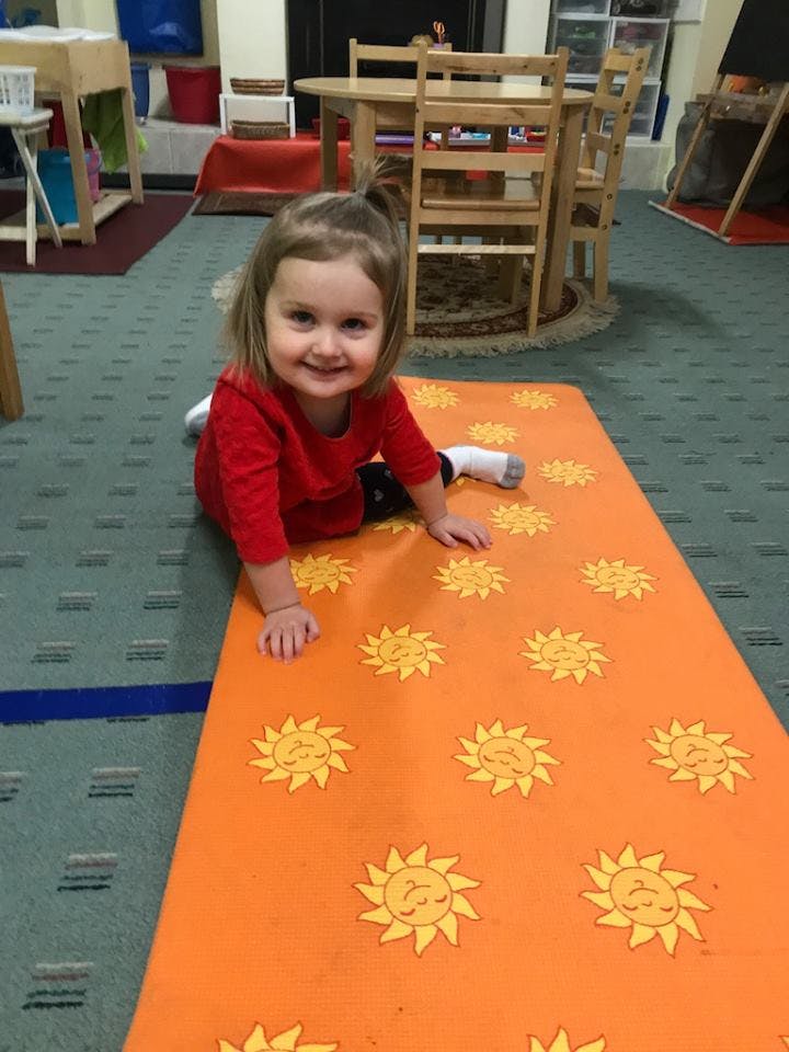 Child in red shirt on an orange mat with suns