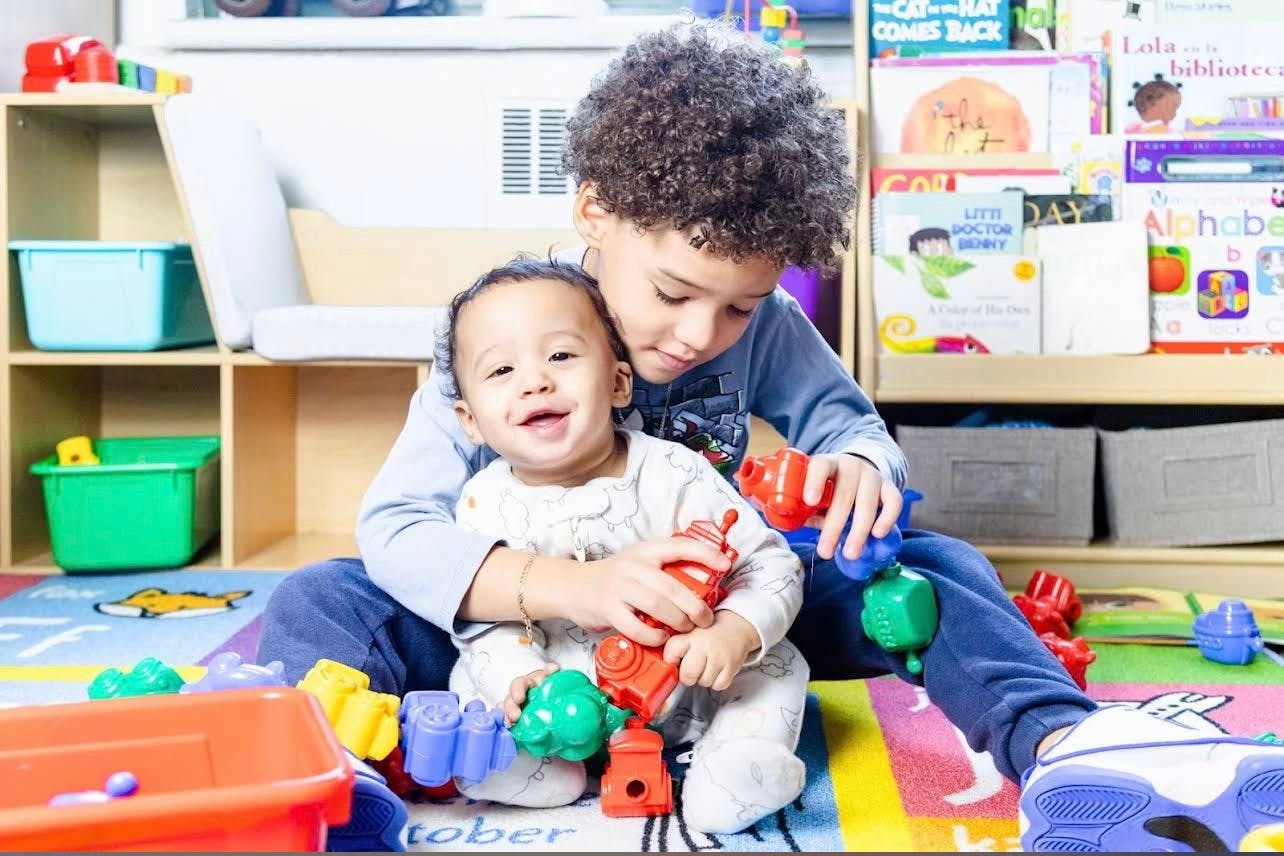 Child holding a baby on a colorful mat with toys
