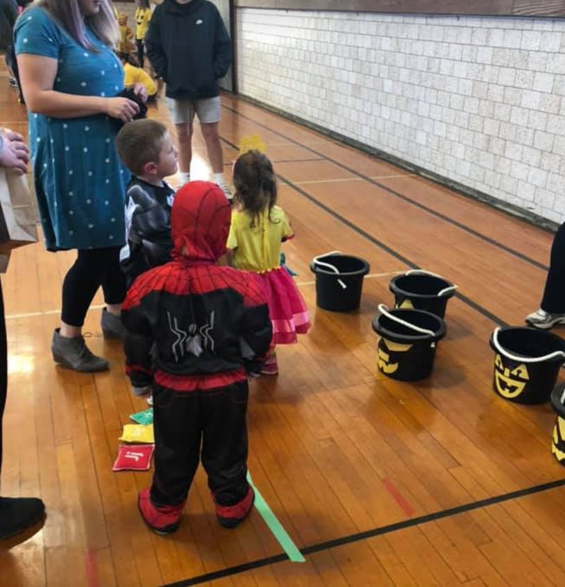 Children in costumes playing a game with buckets on a wooden floor