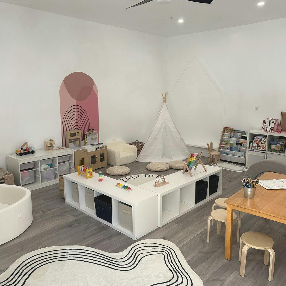 Playroom with white storage cubes, a play kitchen, a teepee, and wooden table