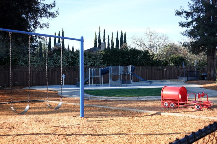 Empty playground with swings and a red train-shaped ride-on toy