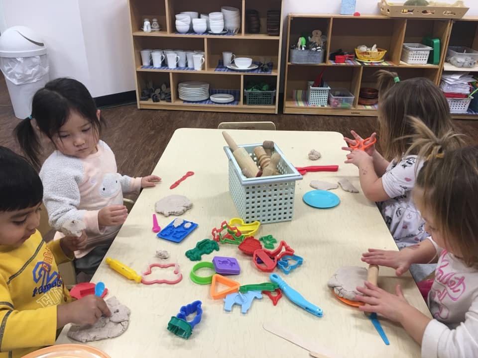 Children playing with modeling clay and cookie cutters at a table