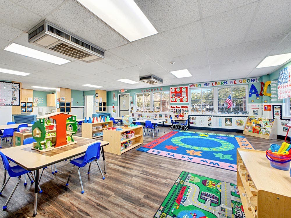 A colorful and tidy classroom with small tables, chairs, and play areas