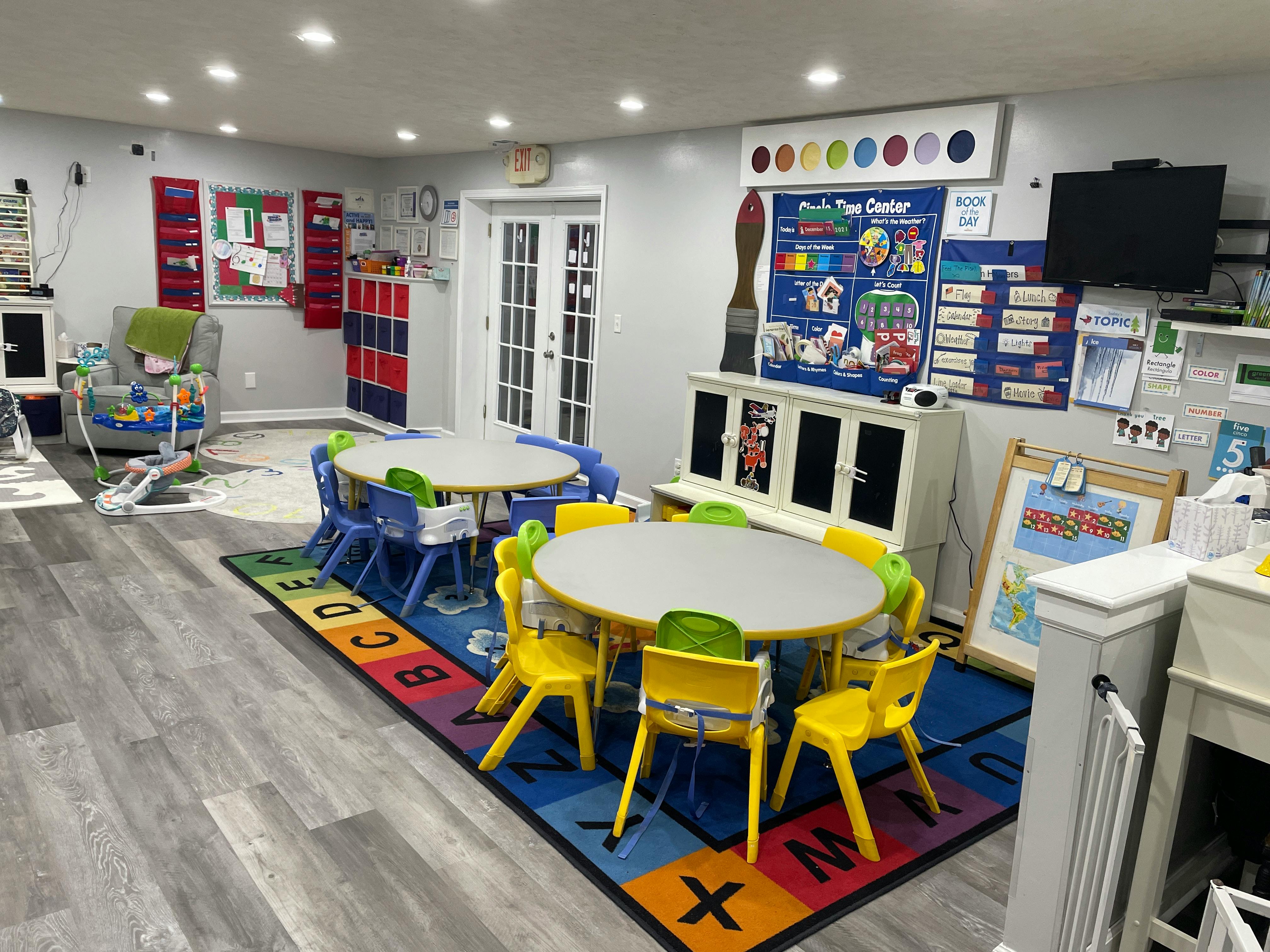 Classroom with small tables and chairs on an alphabet rug