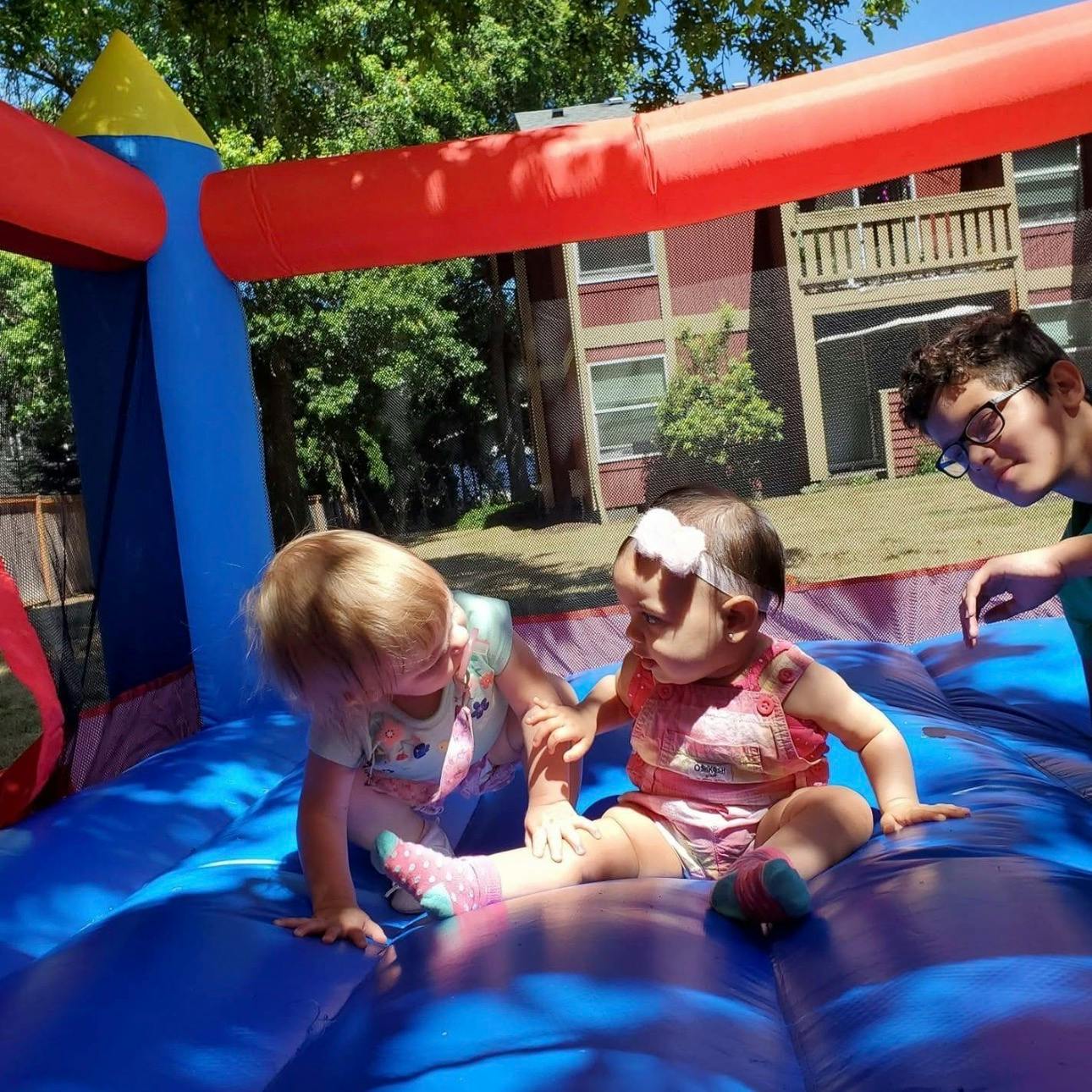 Three children playing on a blue inflatable bouncy house