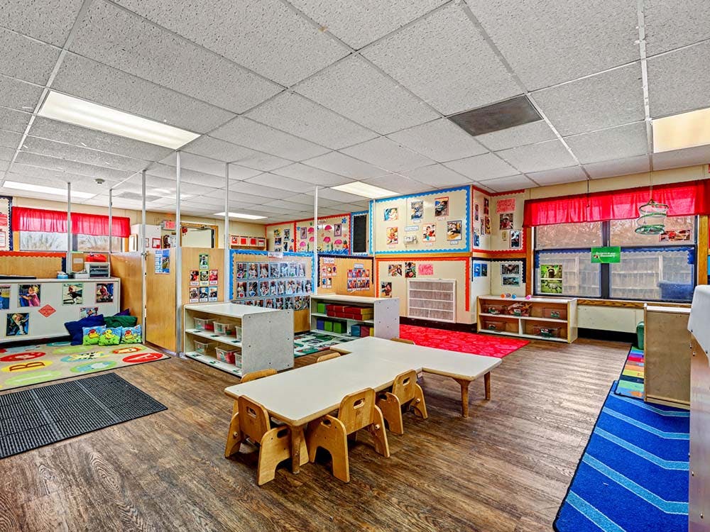 Empty preschool classroom with small tables and chairs