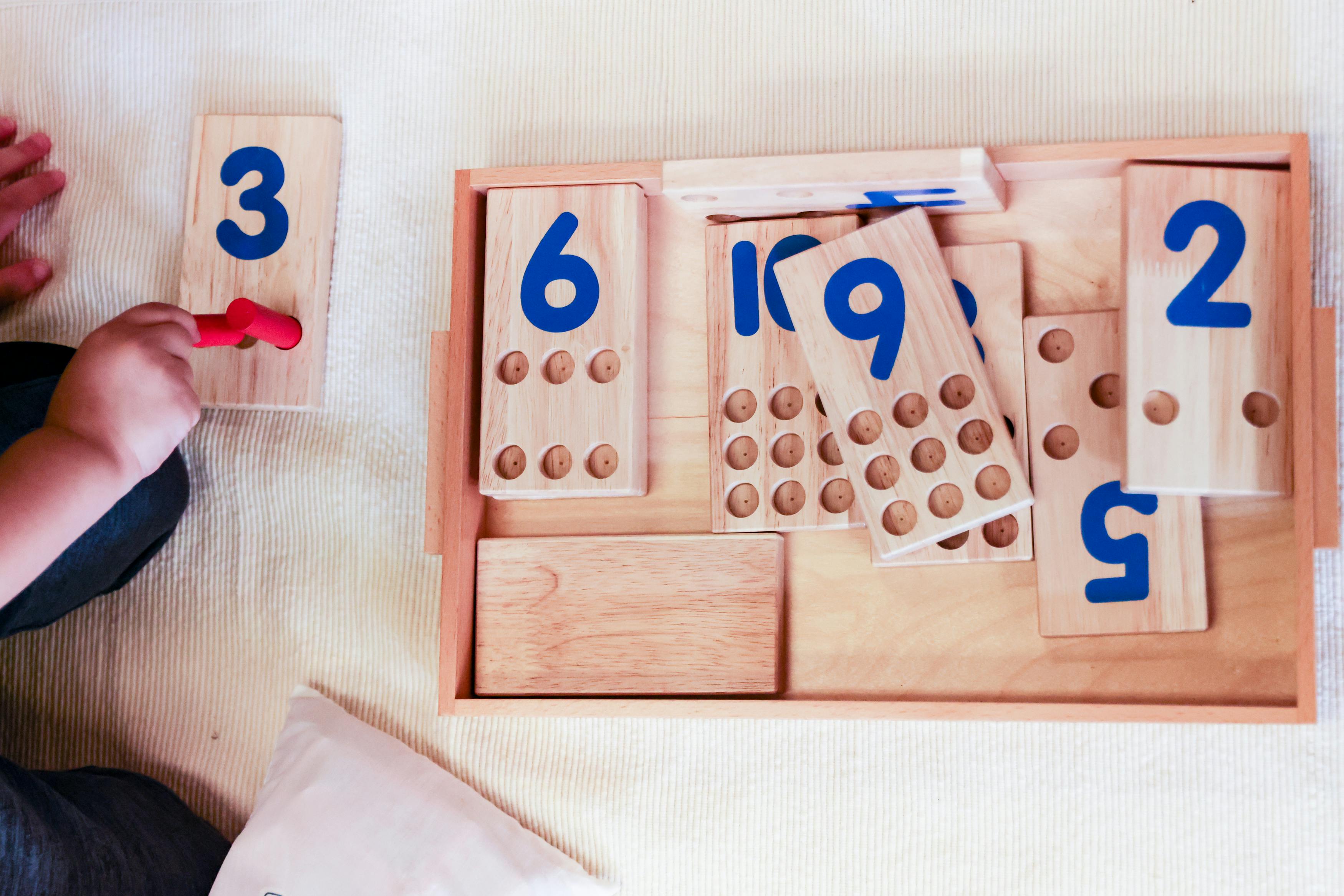 Child playing with wooden number blocks and red pegs