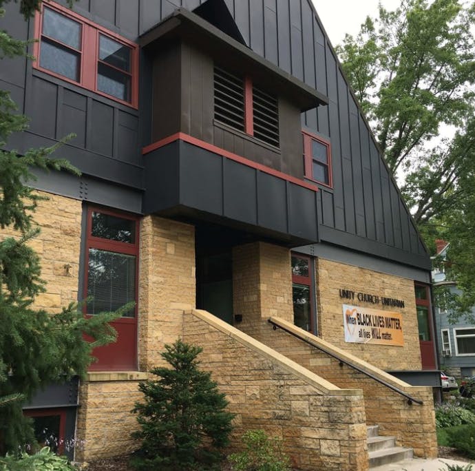Building with stone and dark siding, sign reads "Black Lives Matter"
