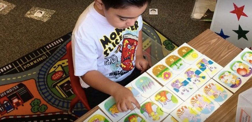 Child playing with colorful picture cards on a table