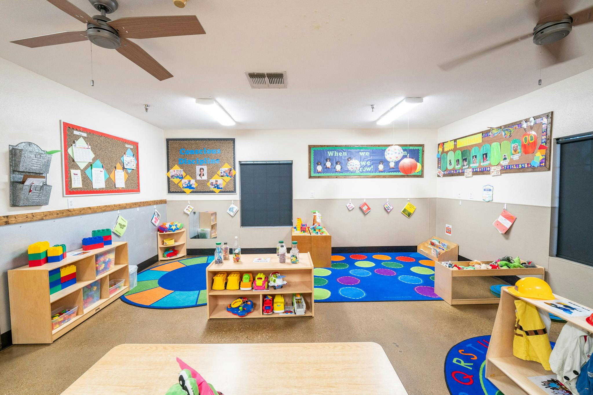 Classroom interior with wooden shelving units, toy vehicles, and colorful rugs