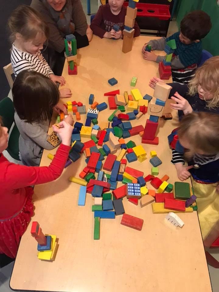 Children playing with colorful wooden blocks at a table