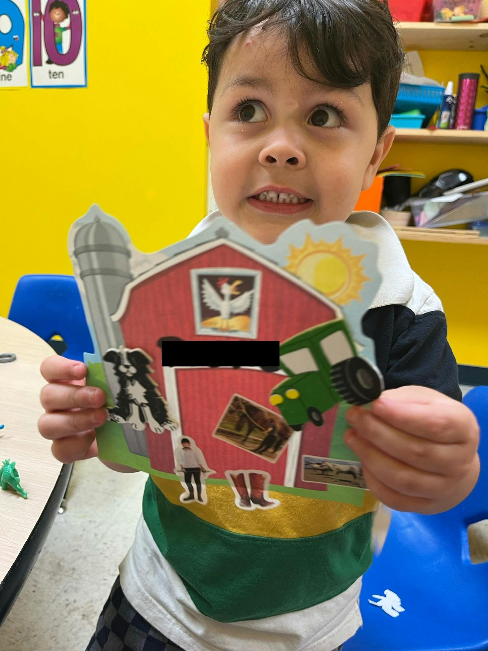 Child holding a paper cutout of a farm scene