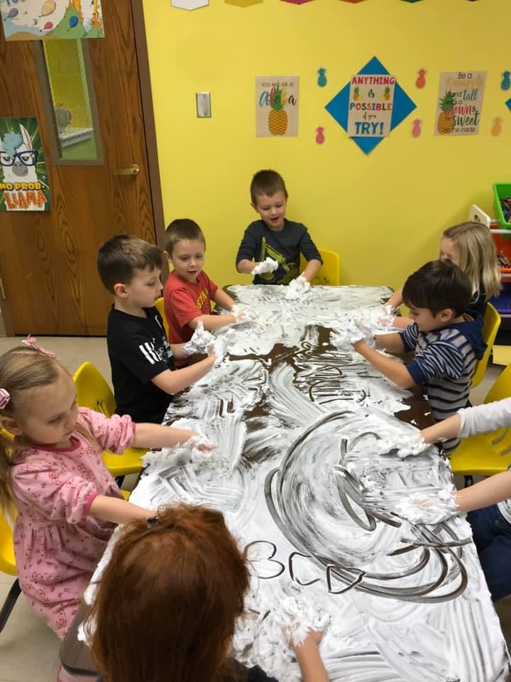 Children playing with shaving cream on a table
