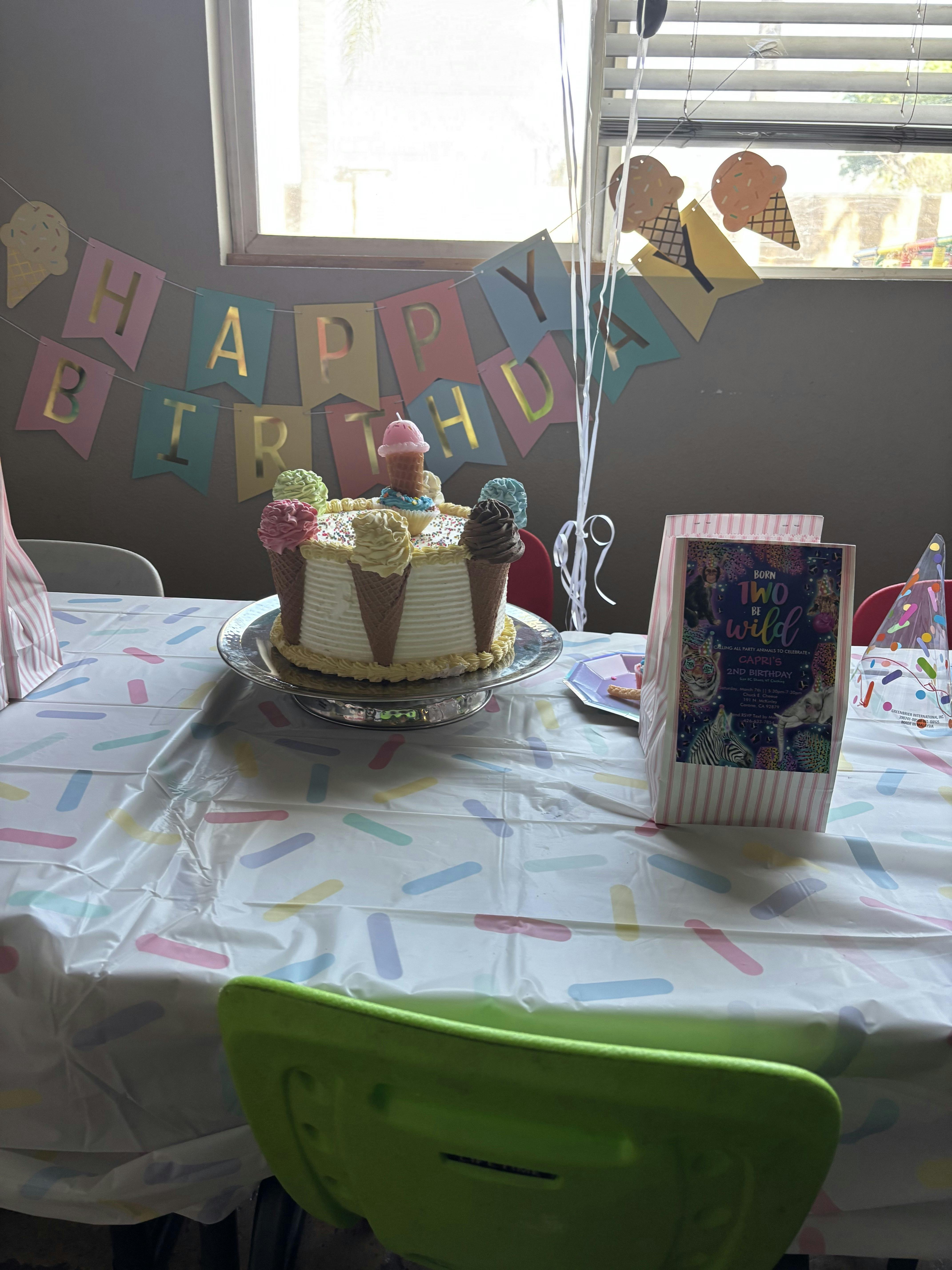 Birthday cake decorated with ice cream cones on a table with a banner that reads "Happy Birthday"
