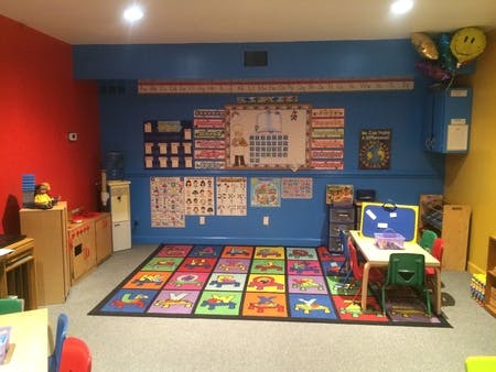 Classroom with colorful rug, small table and chairs, and educational posters