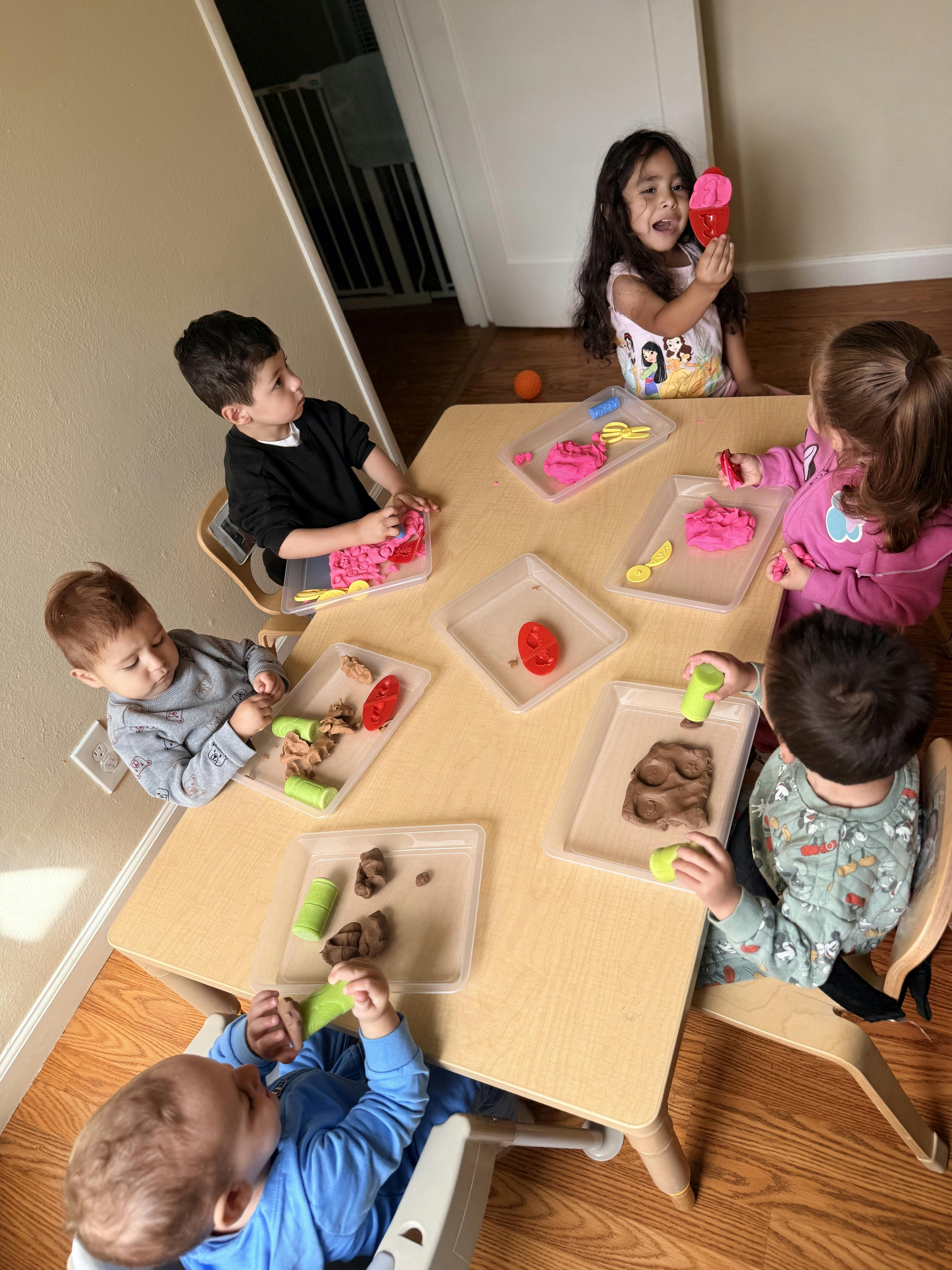 Five children playing with modeling clay at a table
