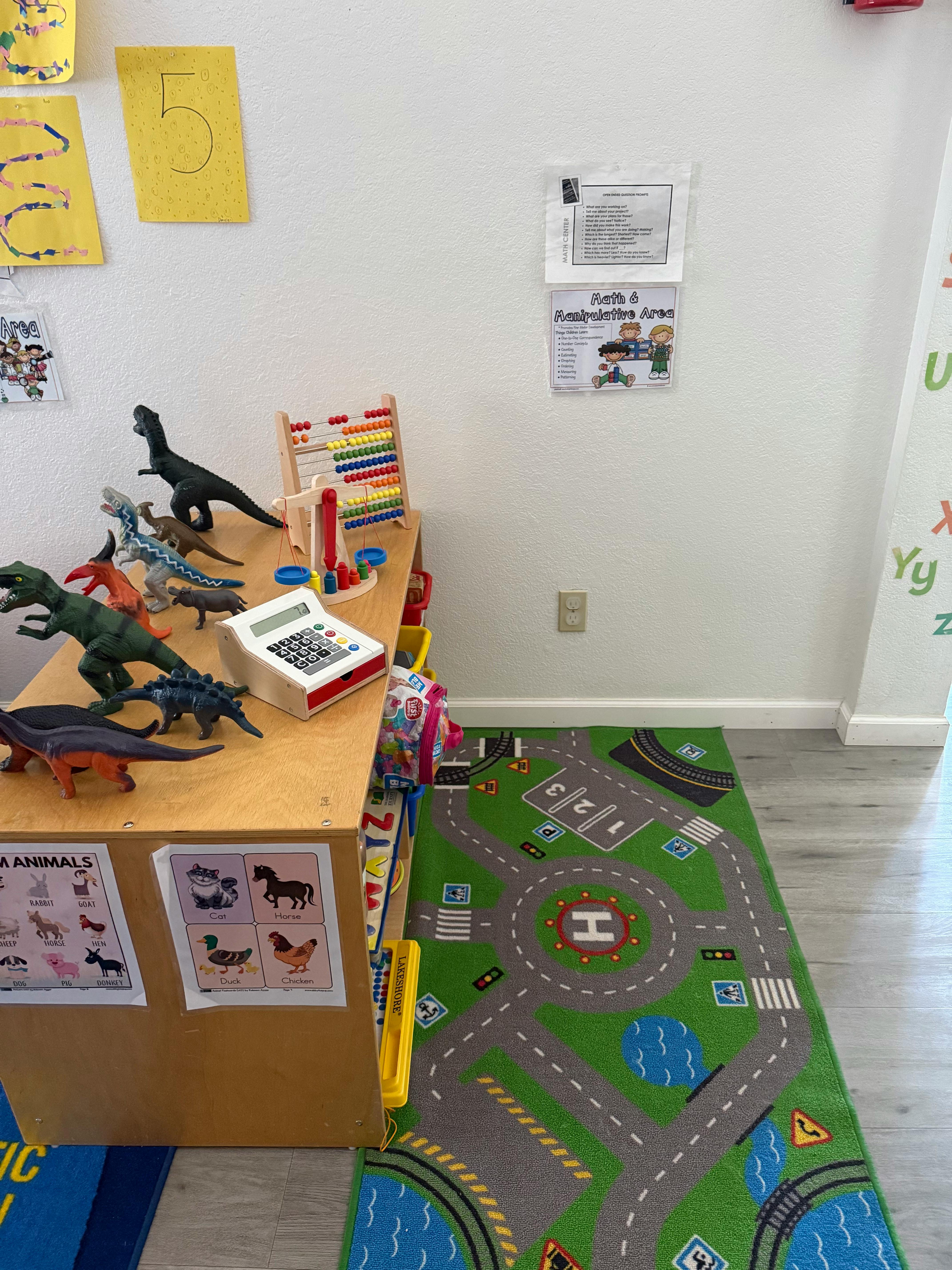 Playroom with dinosaur toys on a table and a road map rug on the floor