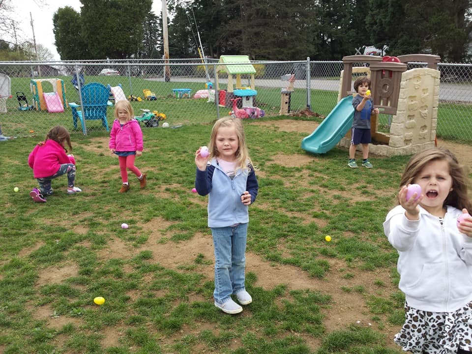 Children holding plastic eggs in a grassy play area