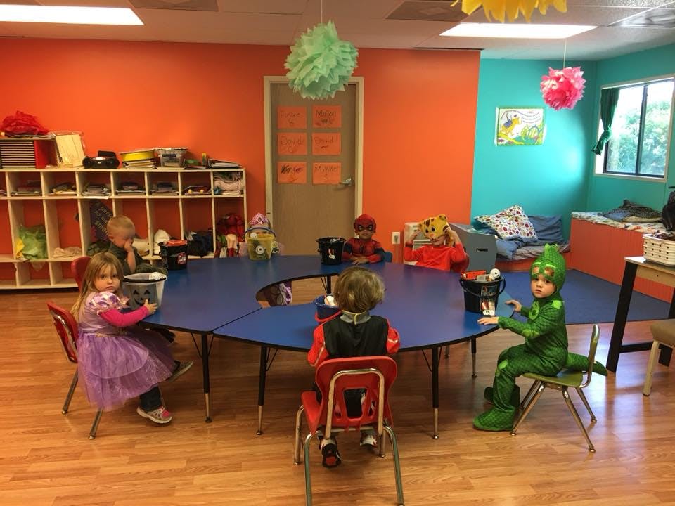 Children sitting at a blue table in a classroom