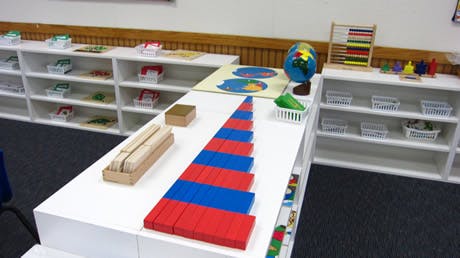 Montessori classroom with learning materials on shelves and a table