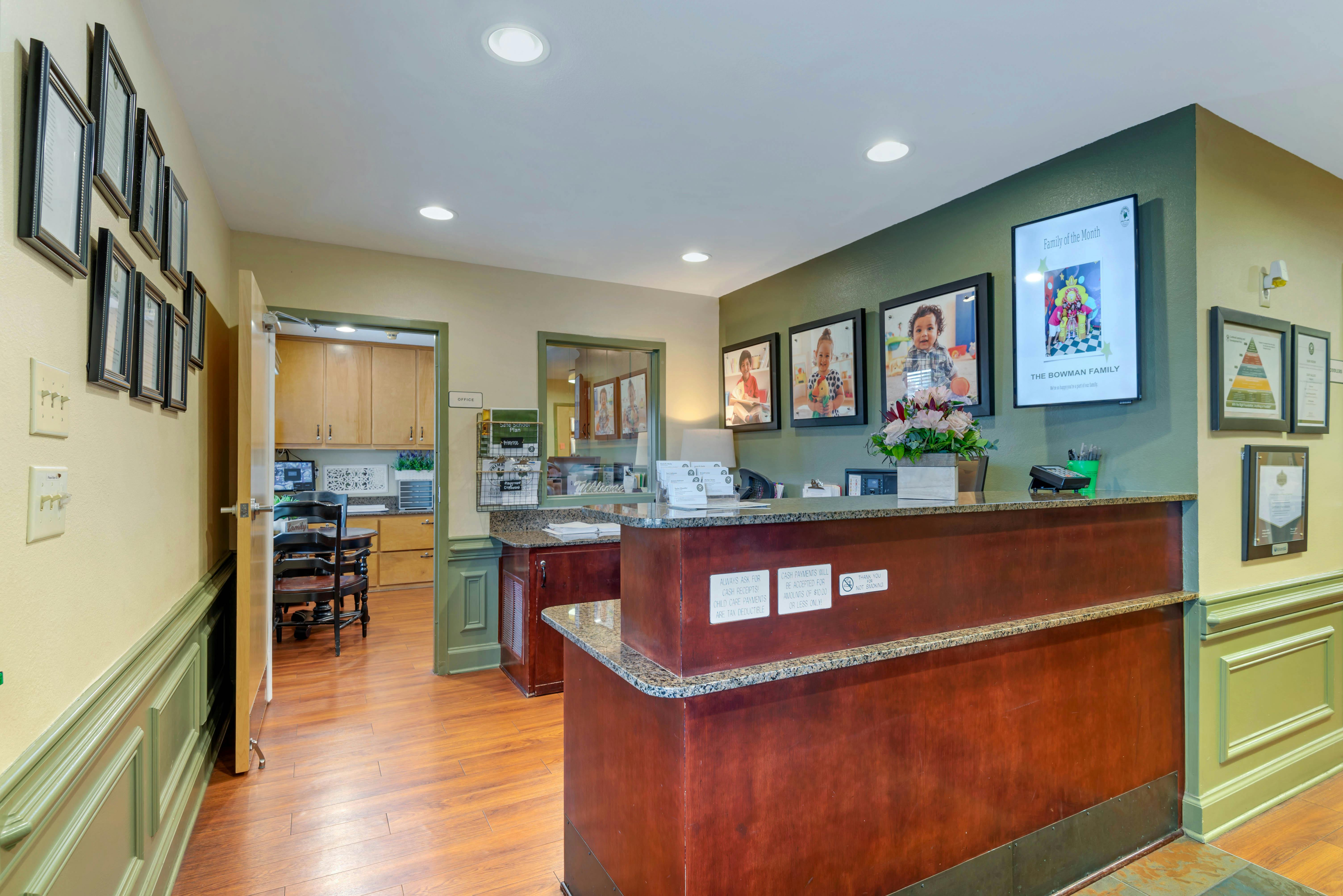 Reception desk with granite counter and framed photos of children on the wall