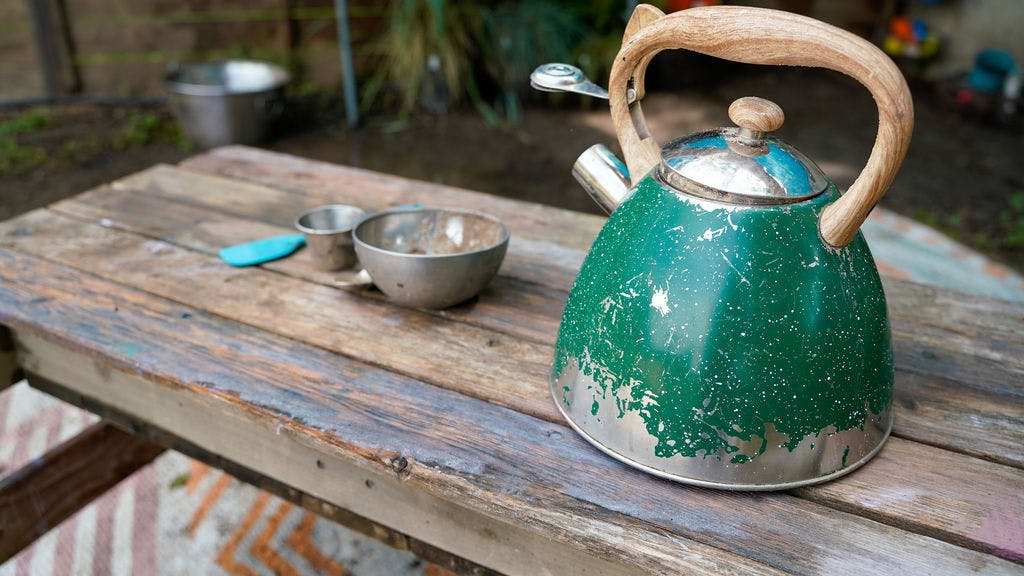 Tea kettle and metal bowls on a wooden outdoor table