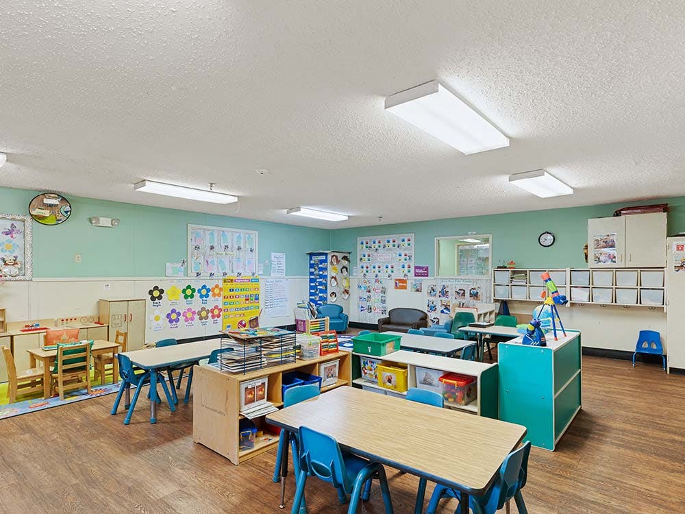 Classroom with small tables and chairs, shelves, and decorations on the walls