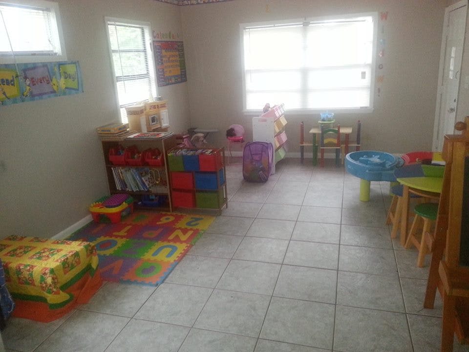 Playroom with colorful rug, toys, and small tables