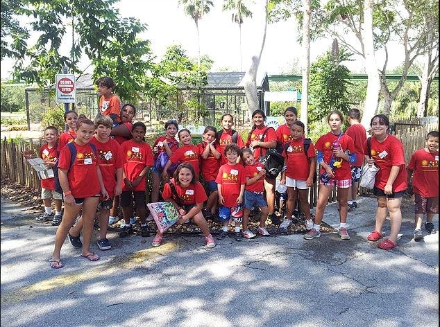 Group of children and teens in red shirts standing outdoors
