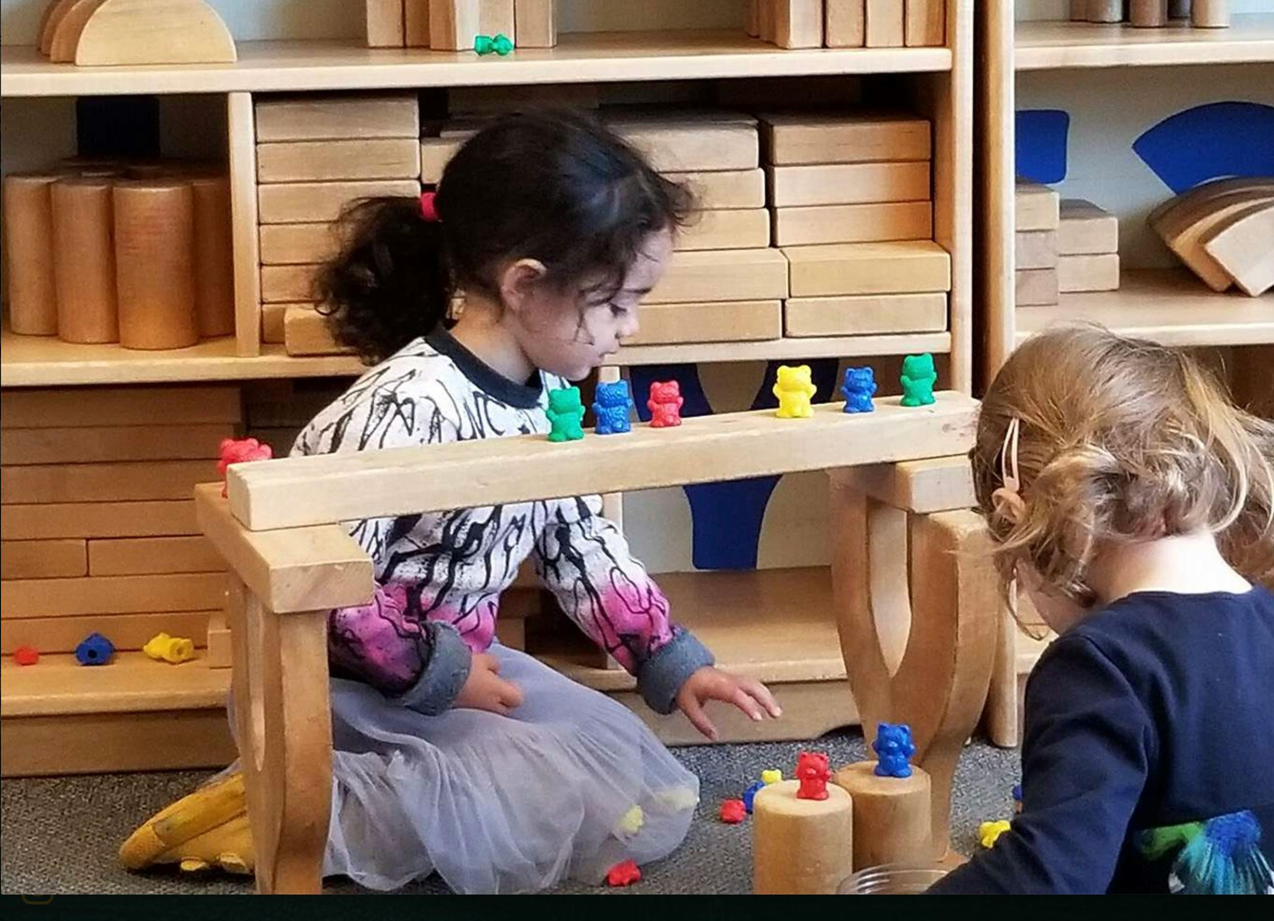 Children playing with small bear figurines on wooden structures