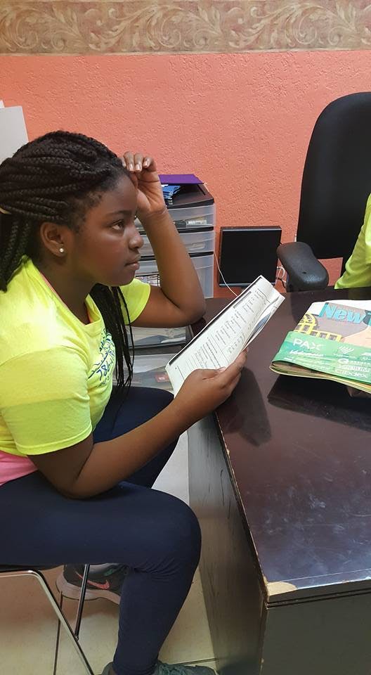 Teen sitting at a desk reading a book