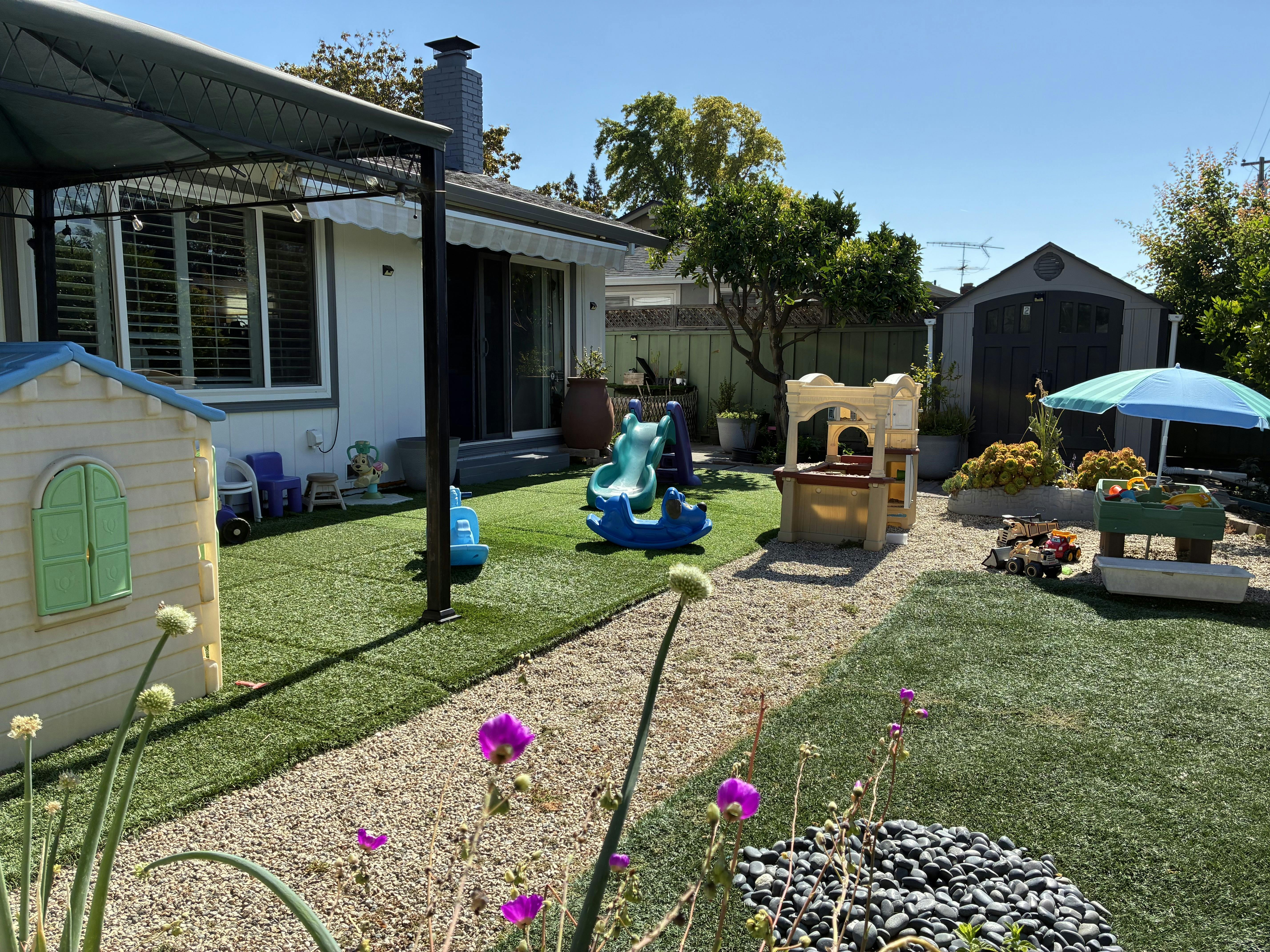 Backyard with artificial turf, playhouse, and various outdoor toys