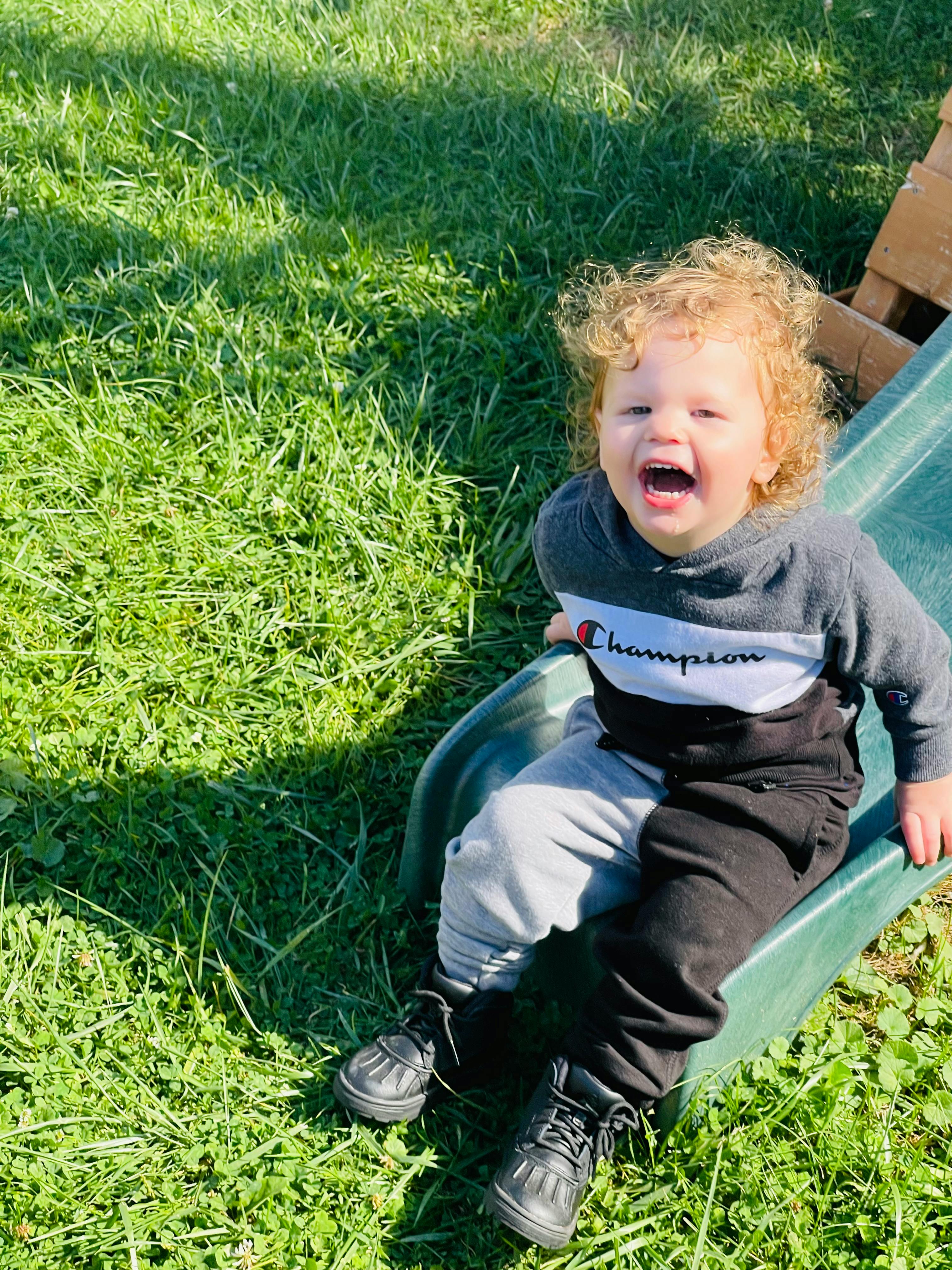 Child with curly hair sitting on a slide
