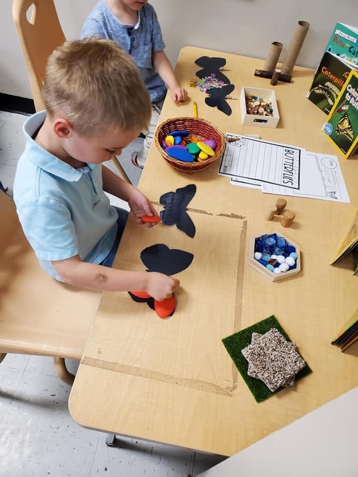 Child playing with butterfly cutouts and craft supplies at a table